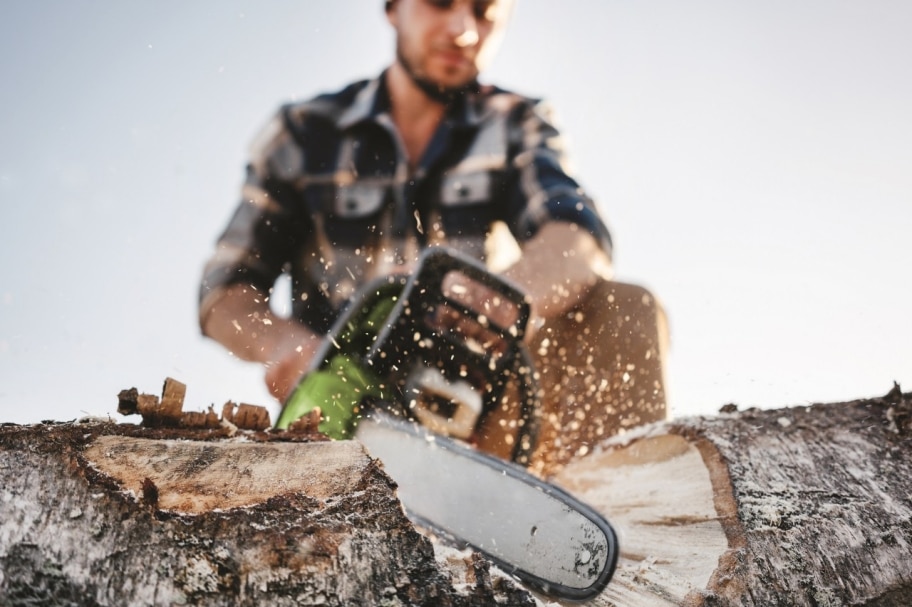 Mann bei der Arbeit sägt Holz mit einer Kettensäge