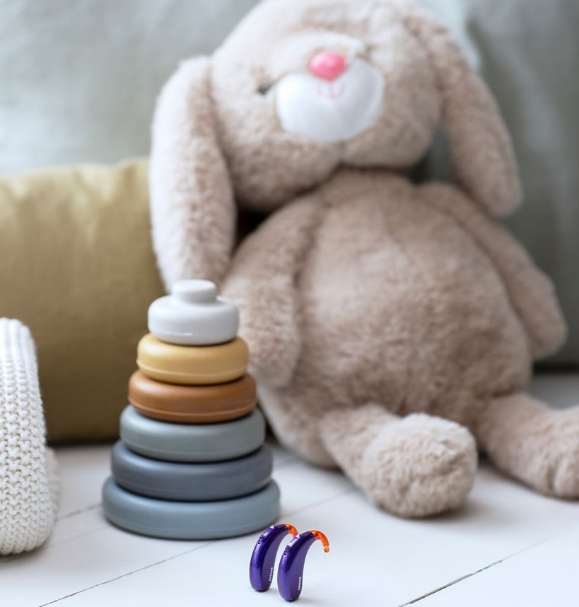 Hearing aids near stuffed animal and baby toy.