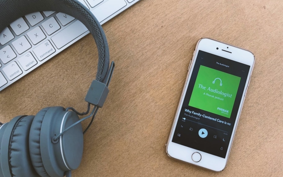 Casque audio placé à côté d’un téléphone portable diffusant le podcast de Phonak